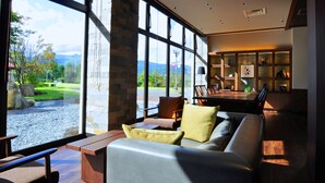 A modern living room with a large window, a sofa, and a dining area.