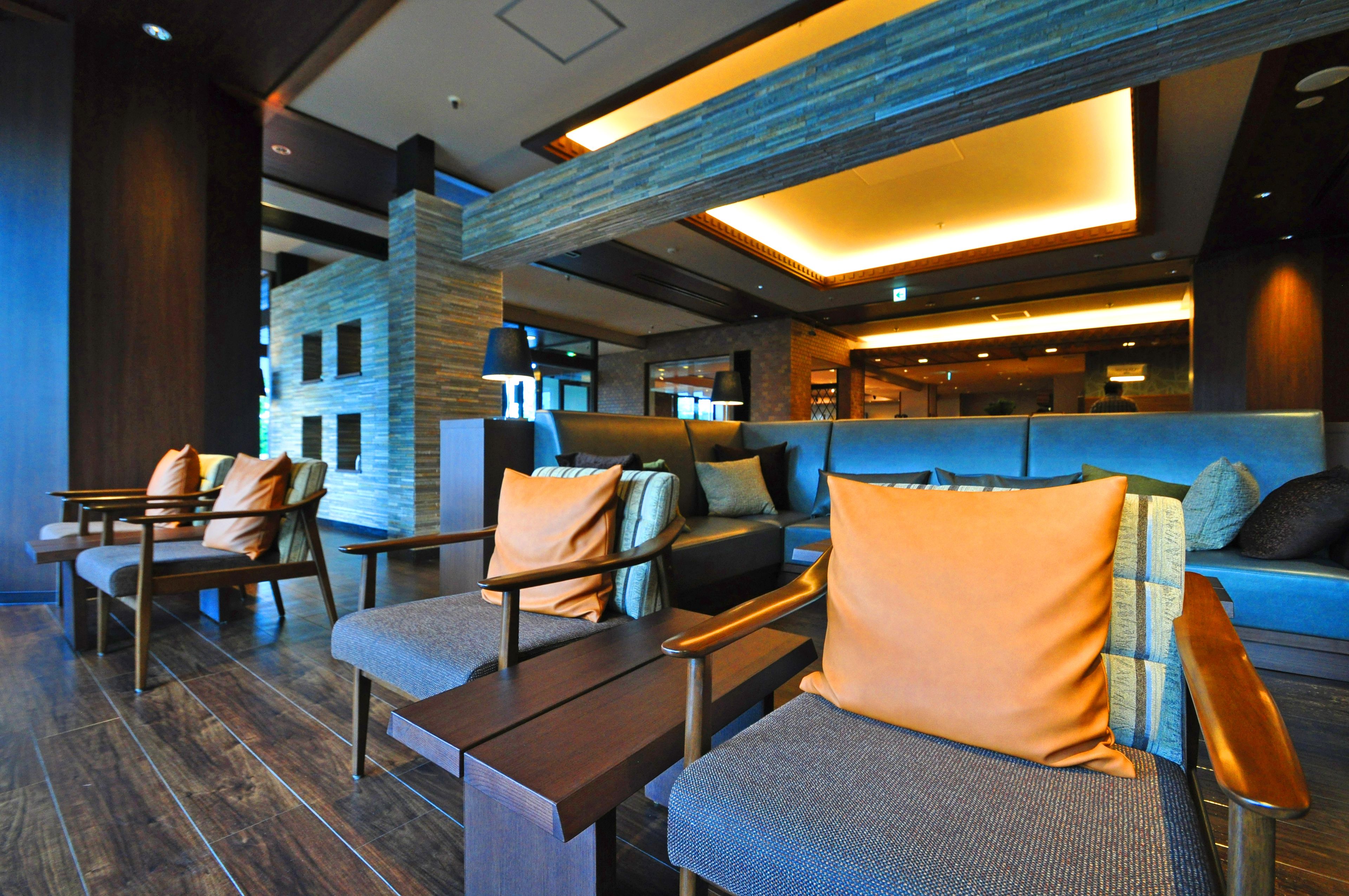 A modern lounge area with seating arrangements, a reception desk, and a stone accent wall.