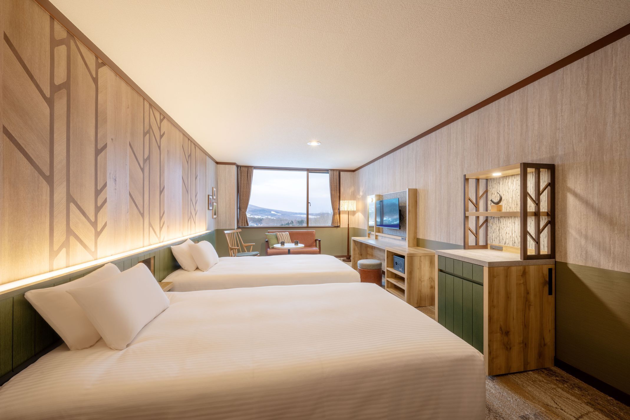 Een hotelkamer met twee bedden, een bureau, een televisie en uitzicht op het omliggende landschap.