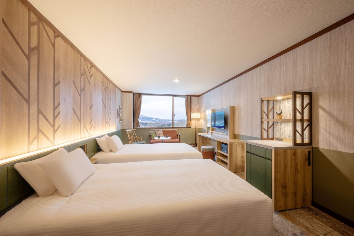 Une chambre d’hôtel avec deux lits, un bureau, une télévision et une vue sur l’extérieur.