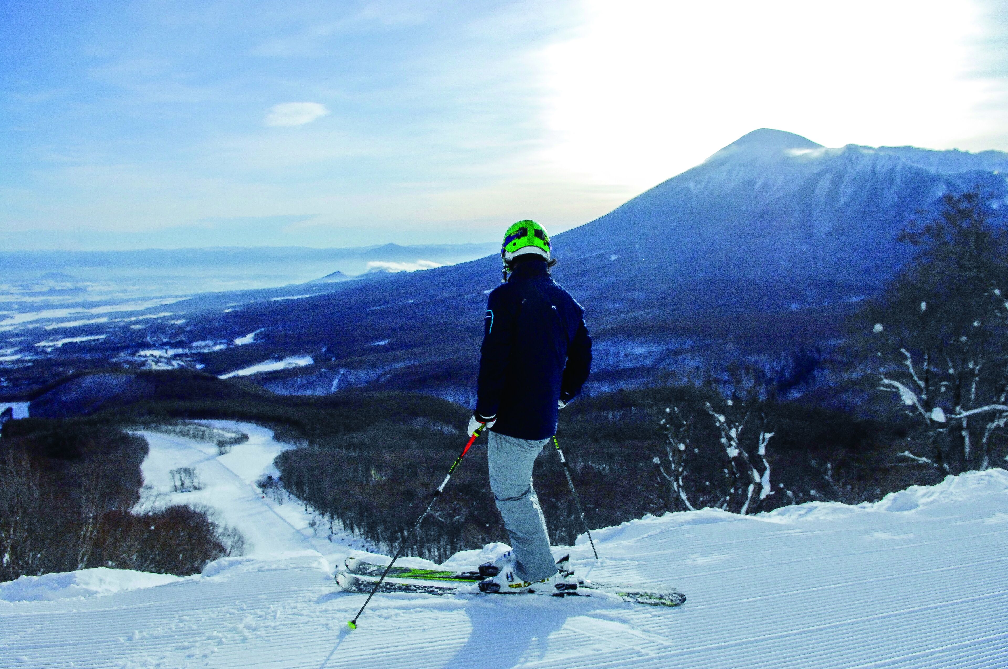 A person skiing on a snowy slope with a mountain in the background.