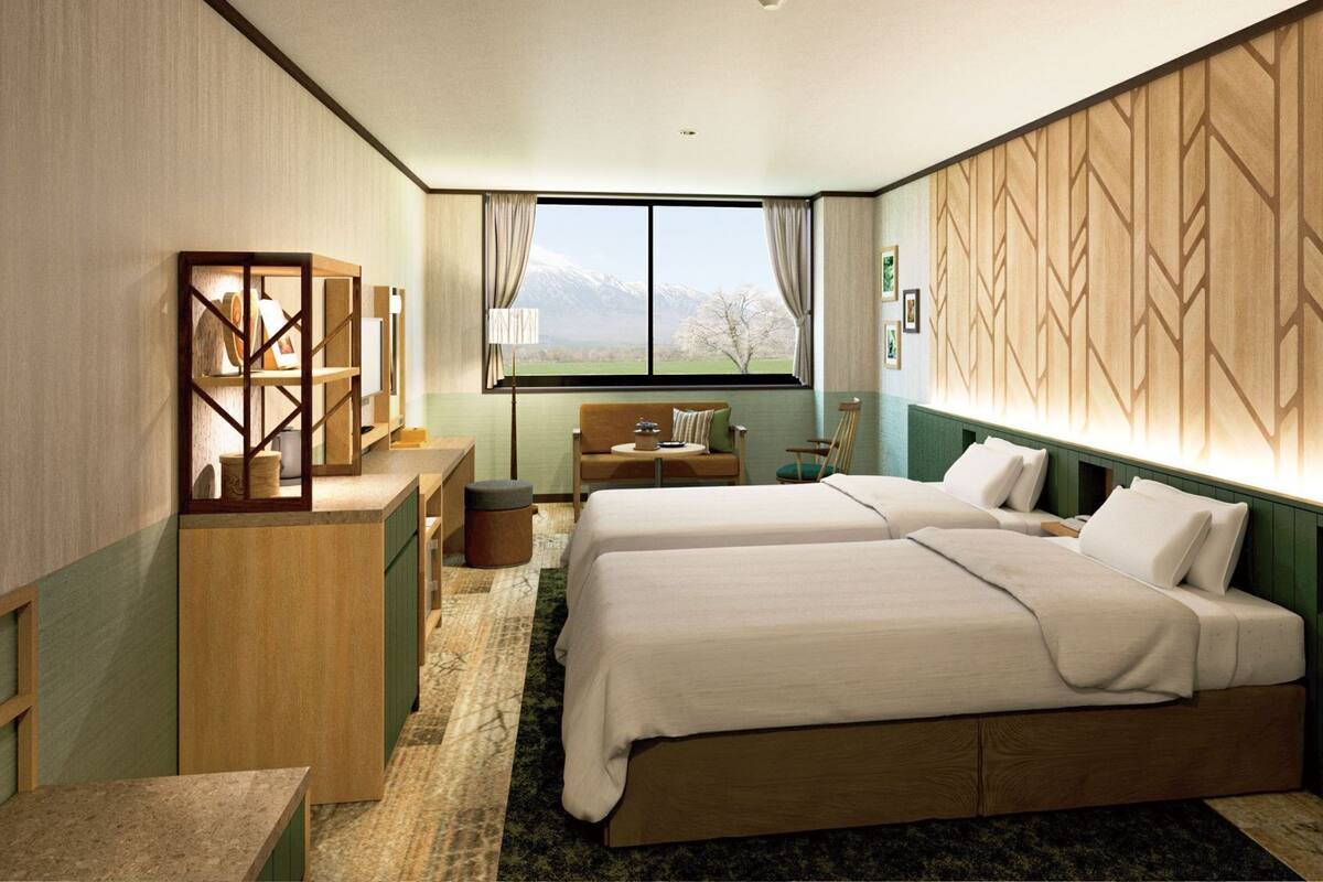 A modern hotel room with two beds, a desk, and a view of mountains through the window.