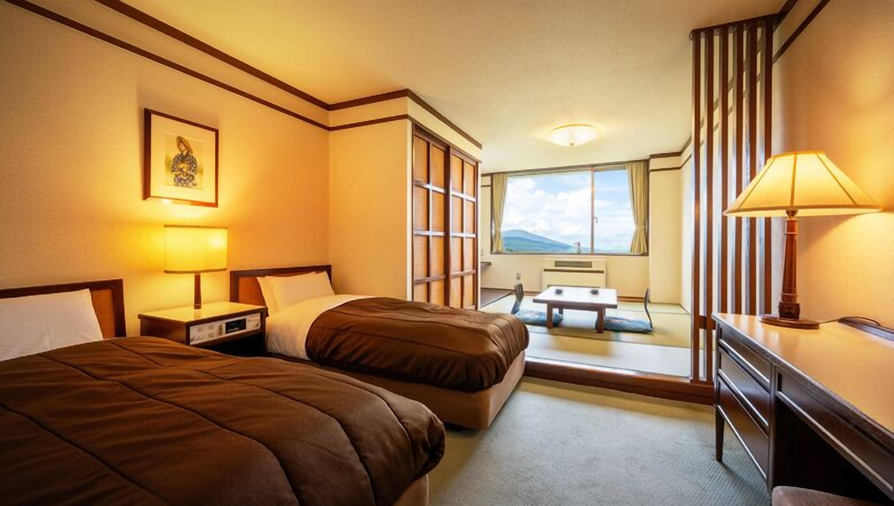 Une chambre d’hôtel avec deux lits, un bureau, une chaise, une fenêtre donnant sur un beau paysage et une lampe.