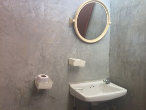 Ein Badezimmer mit Waschbecken, Spiegel und Toilettenpapierhalter.