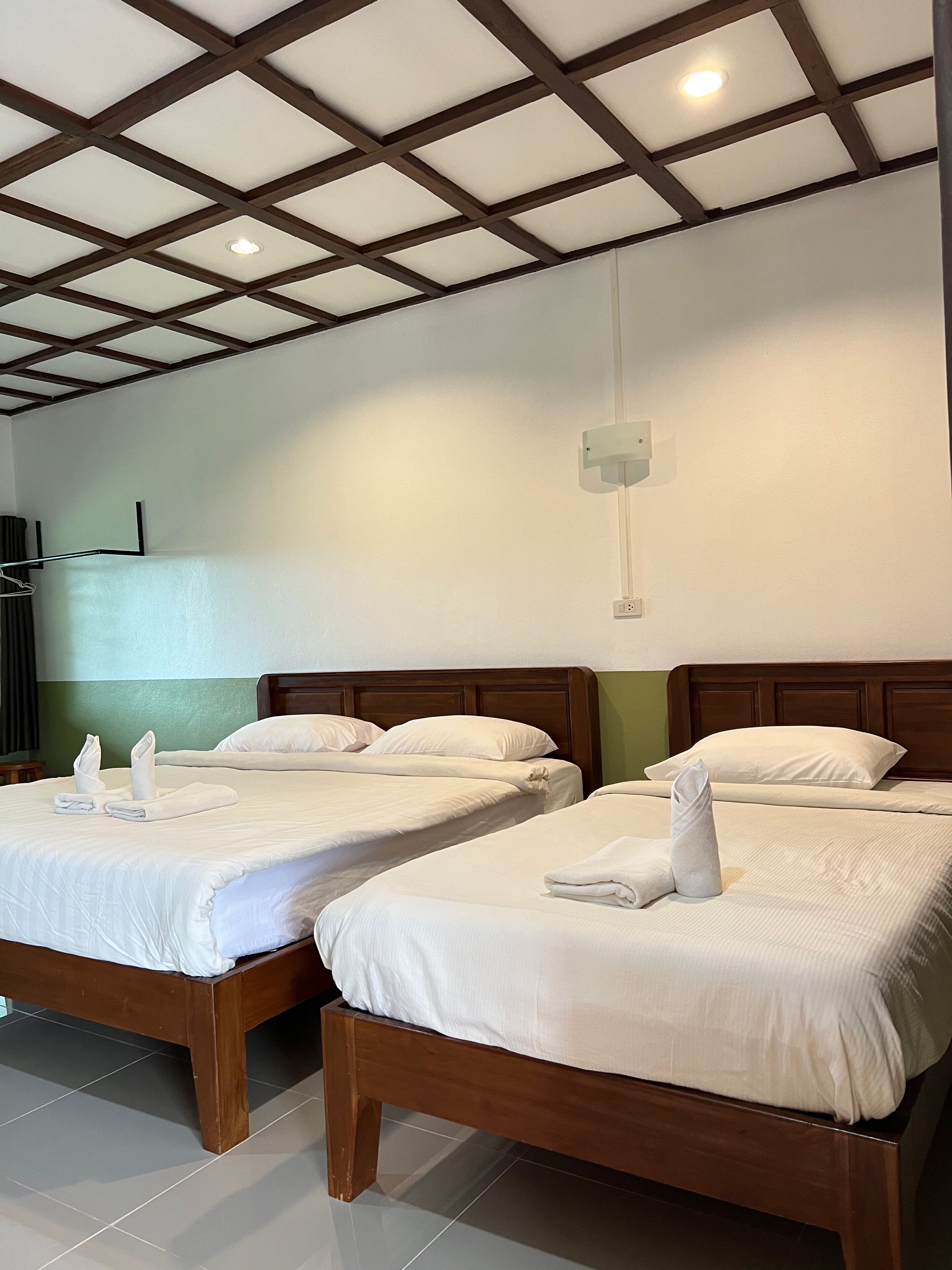 A hotel room with two wooden beds, white bedding, and a simple, clean design.