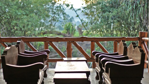 A wooden deck with benches and tables, overlooking a lush green landscape.