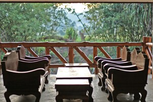 Una terraza de madera con bancos y mesas, con vistas a un paisaje verde exuberante.