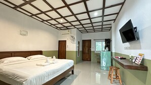 A hotel room with a large bed, a wooden ceiling, a TV mounted on the wall, and a small stool.