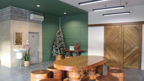 A reception area with a wooden reception desk, a Christmas tree, a potted plant, a sink, and a wooden door.