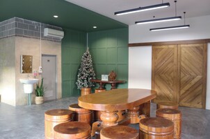 Zona de recepción con un mostrador de madera, un árbol de Navidad, una planta en maceta, un lavabo y una puerta de madera.