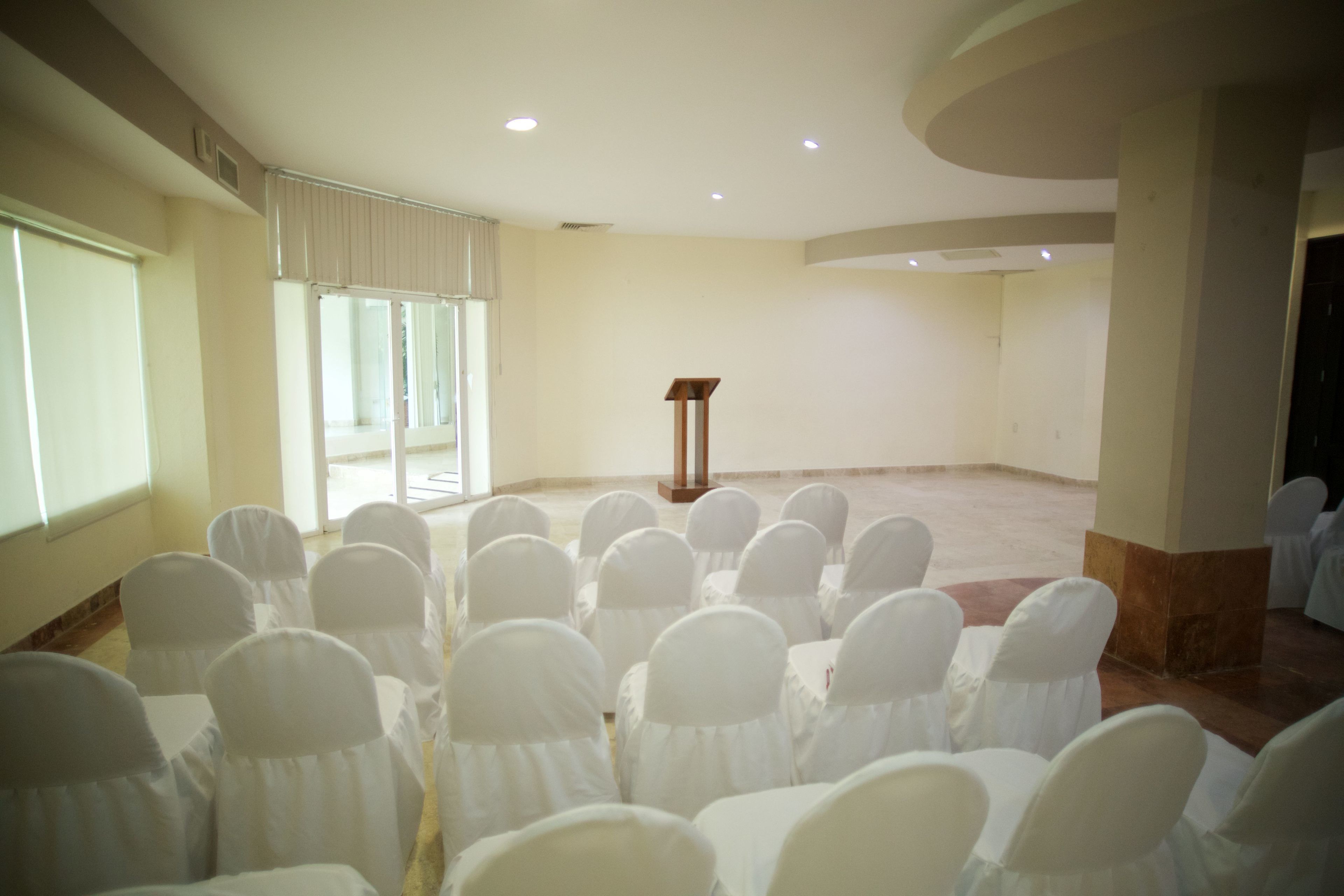 A conference room with rows of white chairs and a podium.