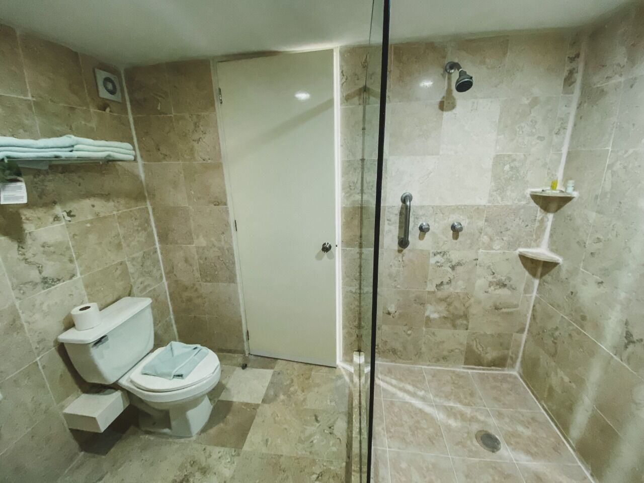 Un baño con inodoro, cabina de ducha y lavamanos.