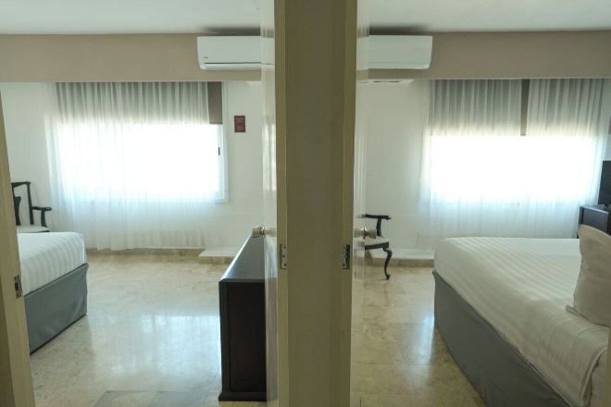 A hotel room with two beds, a desk, and a chair.