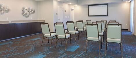 A conference room with a carpeted floor, a whiteboard, and a projector screen.