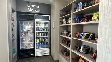 En hjørnebutik med kølevarer og tørlagte varer, hylder fyldt med snacks og drikkevarer, og et rent, moderne indretning.