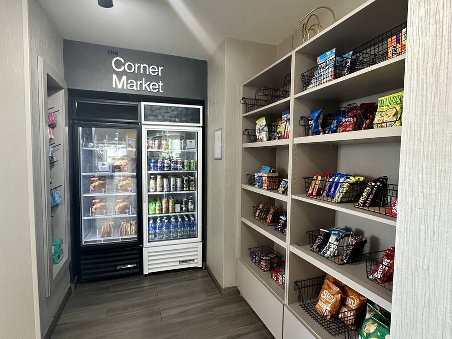 En hjørnebutik med kølevarer og tørlagte varer, hylder fyldt med snacks og drikkevarer, og et rent, moderne indretning.