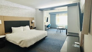 A hotel room with a large bed, a desk, a chair, and a television.