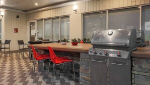 An outdoor kitchen area with a built-in grill, stone accents, and a checkered floor. - TownePlace Suites by Marriott McAllen Edinburg (Edinburg)