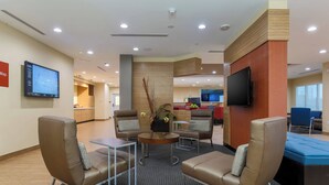 A modern lobby with leather chairs, a coffee table, a flat-screen TV, and a reception desk. - TownePlace Suites by Marriott McAllen Edinburg (Edinburg)