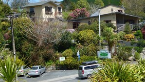 A two-story building with a balcony, surrounded by lush greenery and a parking area. - Waitomo Caves Guest Lodge (Waitomo Caves)