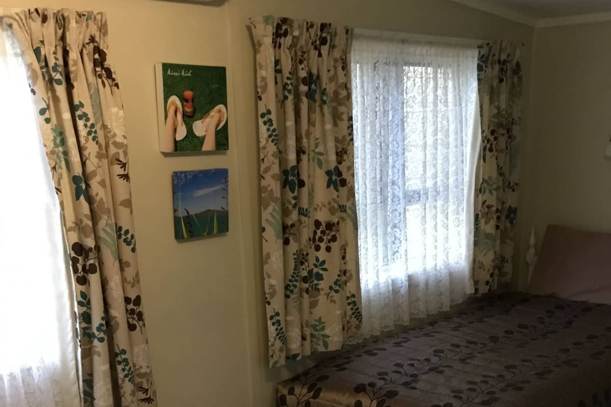 Ein Zimmer mit zwei Betten, Vorhängen mit Blumenmuster und einer Wandklimaanlage.