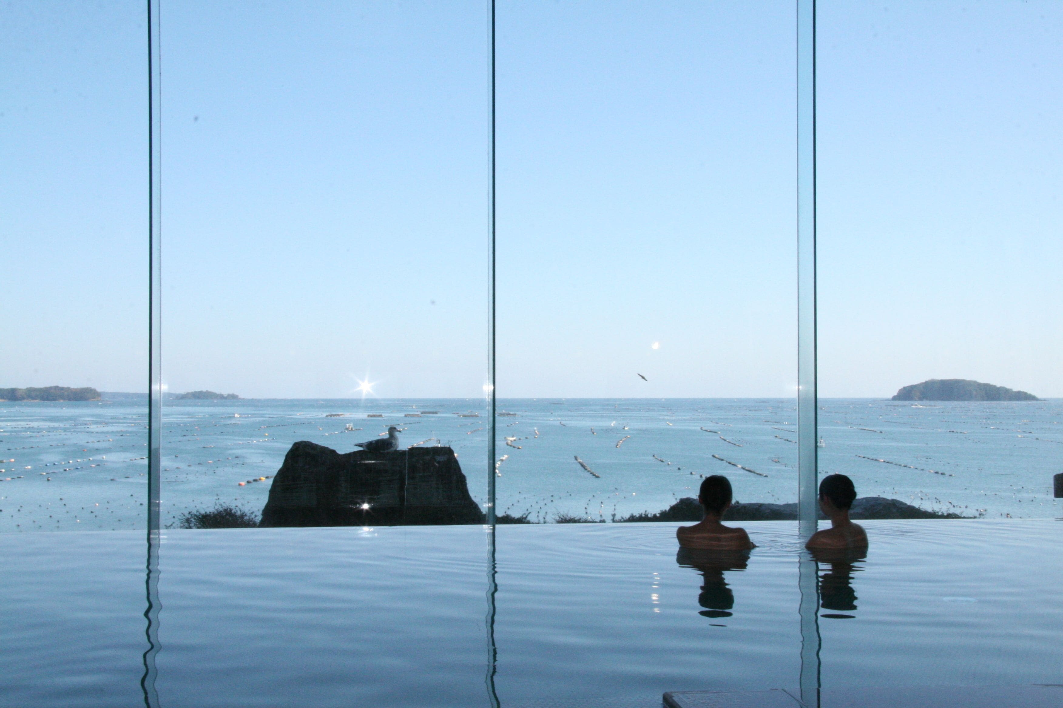 An infinity pool with a clear view of the ocean and distant islands.