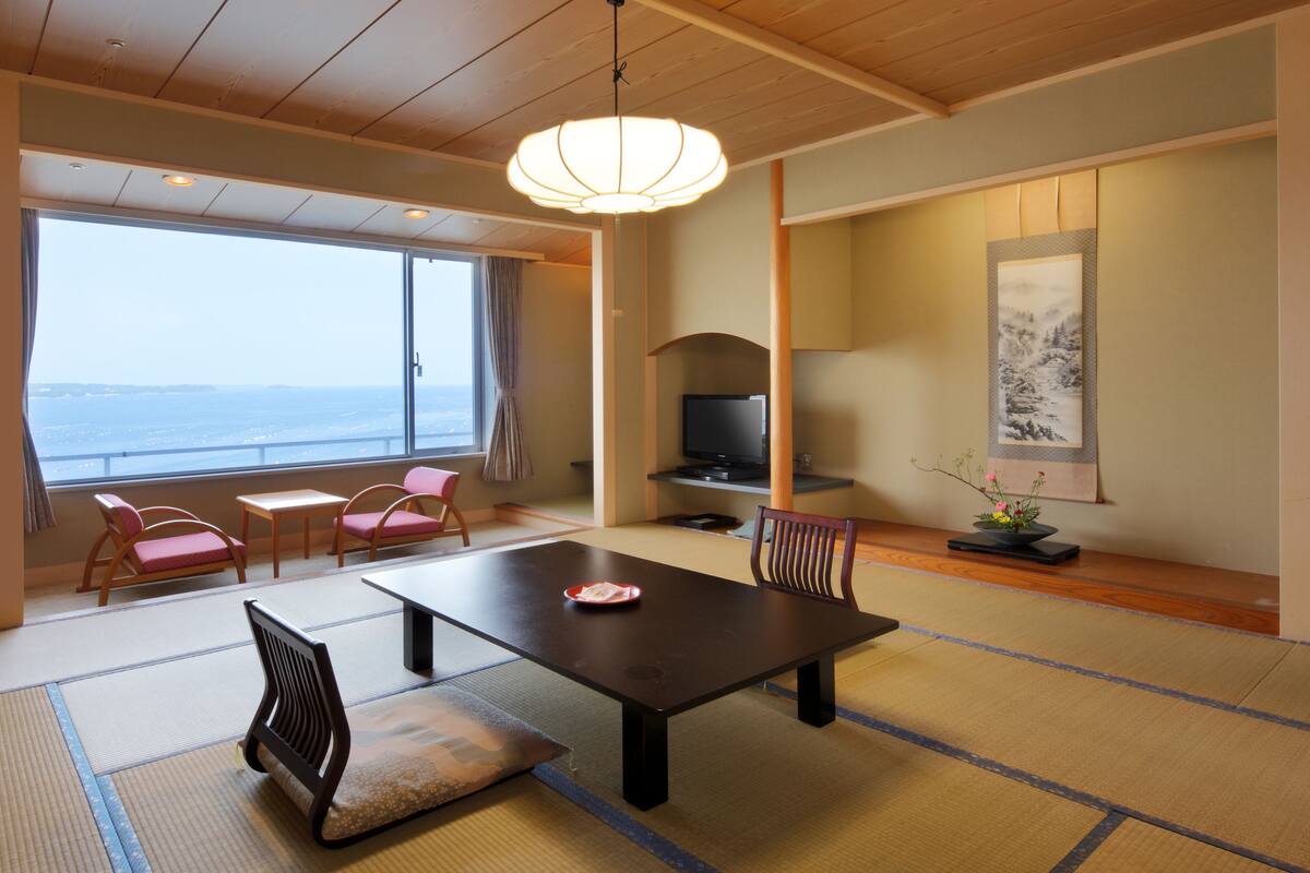 A traditional Japanese room with tatami flooring, a low table, and a television.