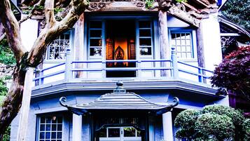 Un edificio tradicional con un balcón, una entrada decorativa y un jardín.