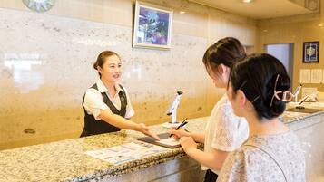 A reception desk with a receptionist, a clock, and a framed artwork on the wall.