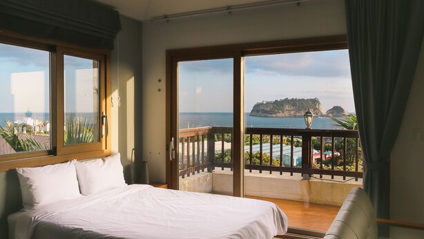 Ein Hotelzimmer mit Bett, einem Balkon mit Meerblick und einem Stuhl.