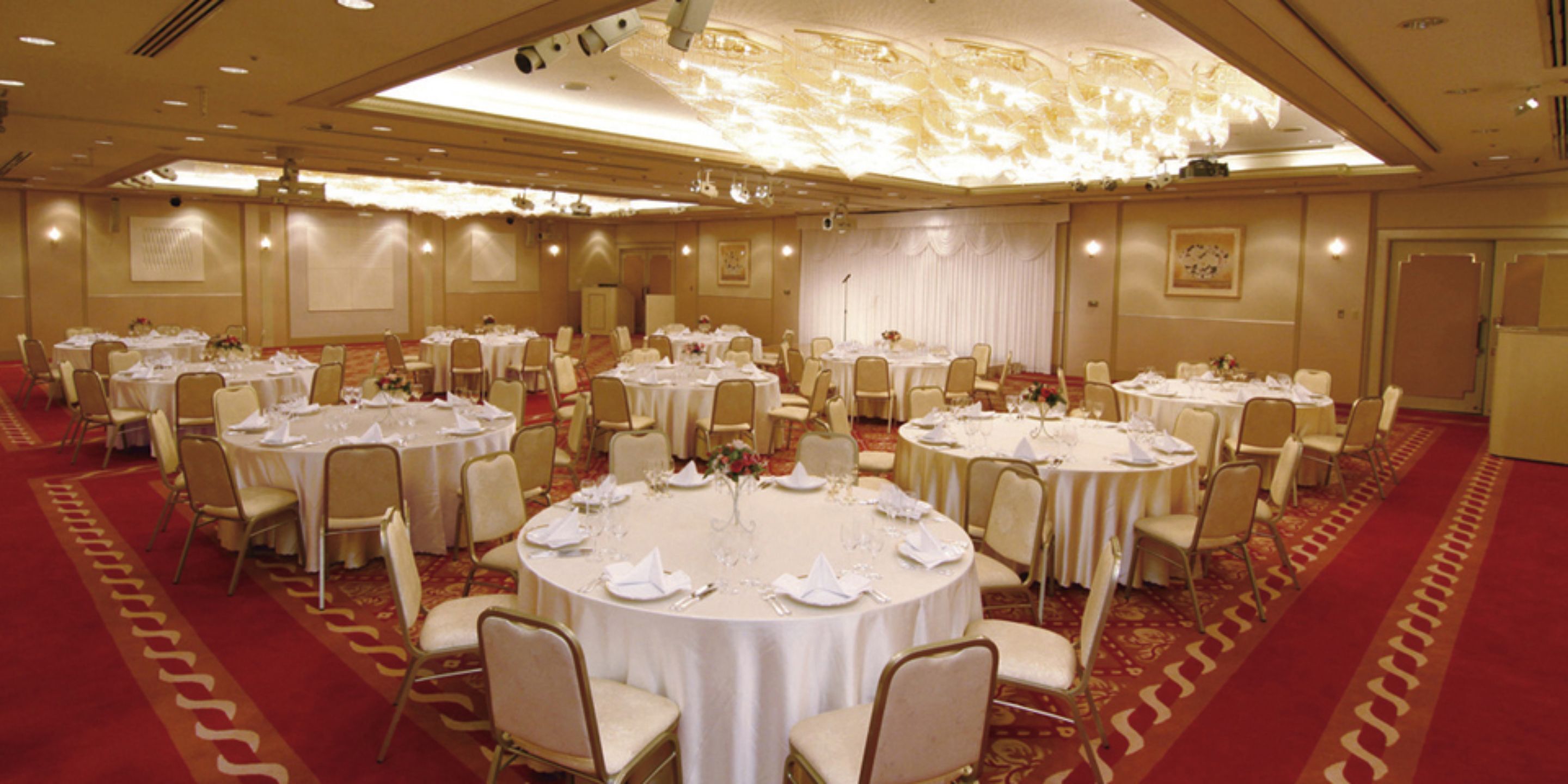 Un salón de banquetes con mesas redondas dispuestas en filas para cenar.