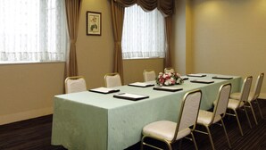 A conference room with a long table, white chairs, and a floral centerpiece. - Hotel Green Tower Makuhari (Chiba)
