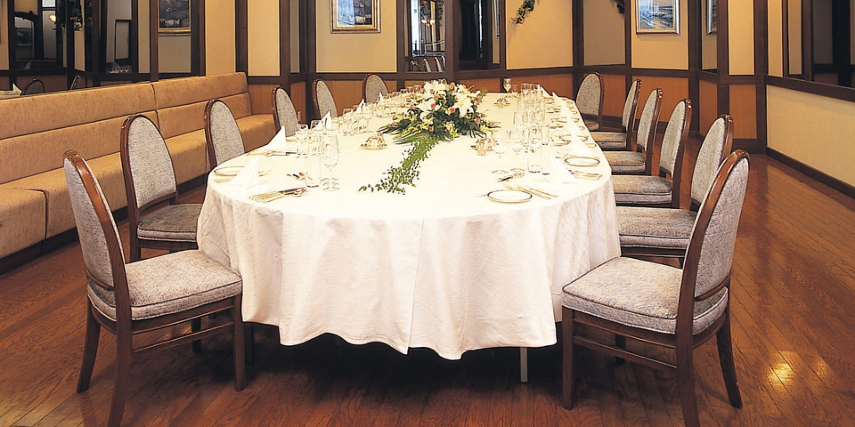 A round dining table set for a formal event with chairs, a white tablecloth, and floral centerpieces.