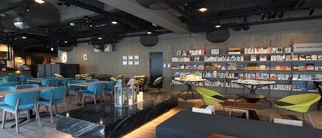 A modern library with seating areas, bookshelves, and a central table.
