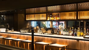A bar area with wooden stools, a counter with various bottles, and a modern design with vertical slats.