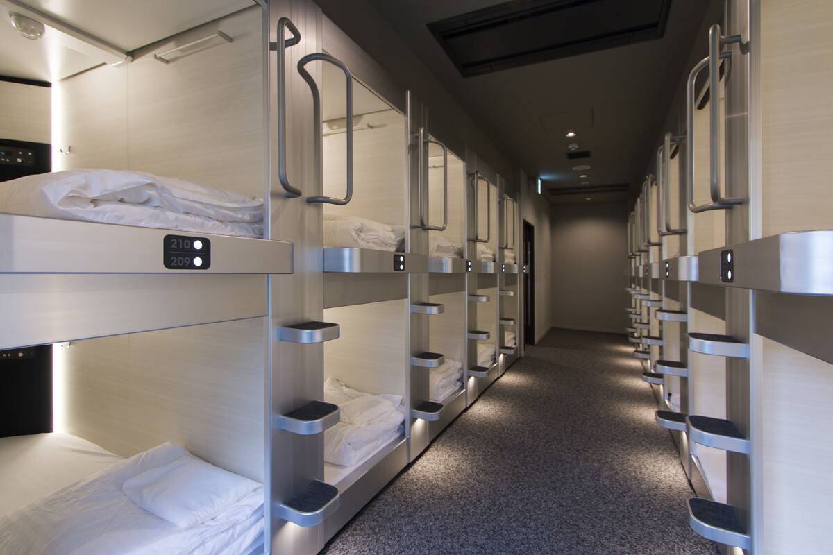 A corridor with bunk beds, each with a control panel and a shelf.