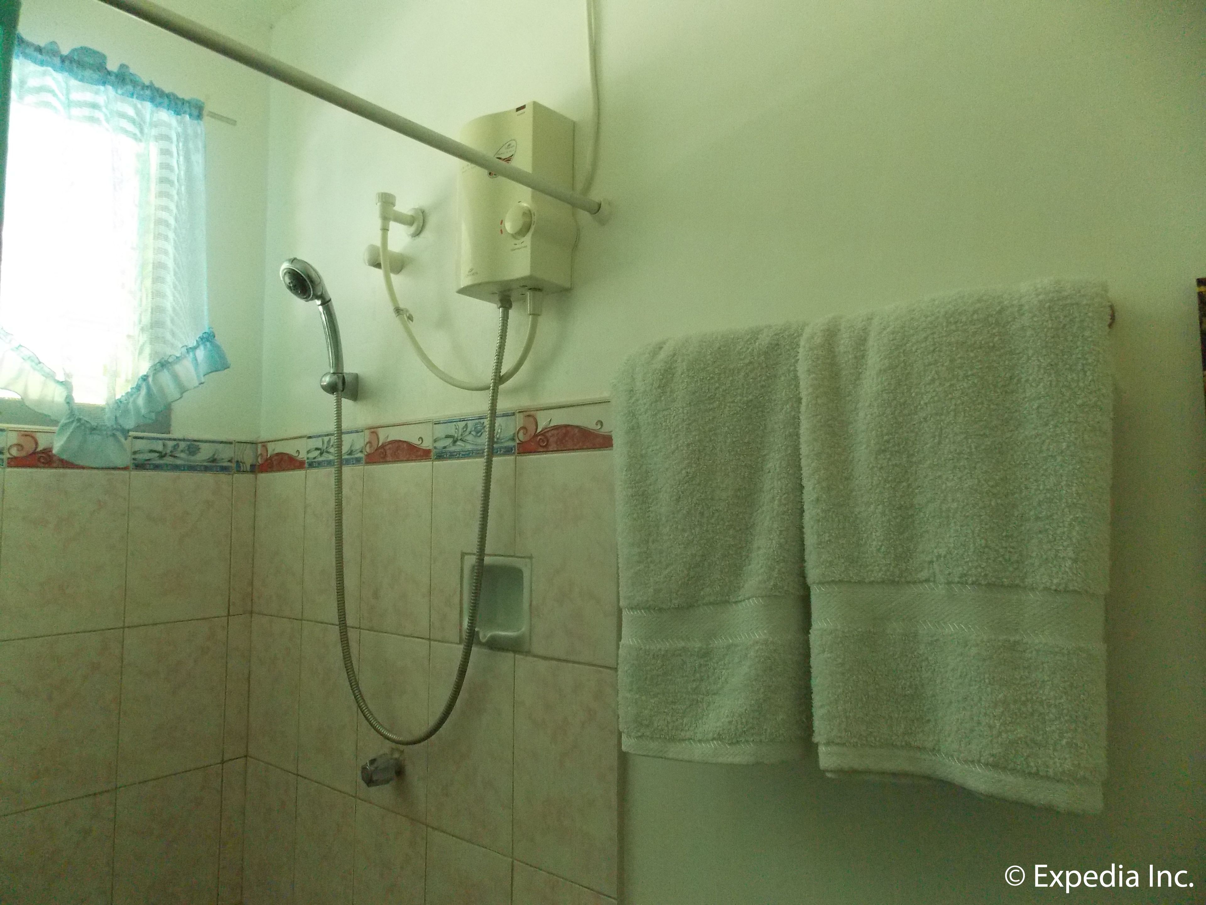 Un bagno con doccia, asciugamano e finestra con tende.
