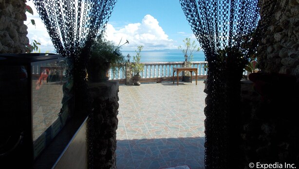 Habitación con paredes de piedra y vista al mar a través de una ventana con cortinas negras.