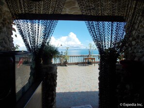 A stone-walled room with a view of the sea through a window with black curtains. - Baluarte de Argao Beach Resort (Argao)