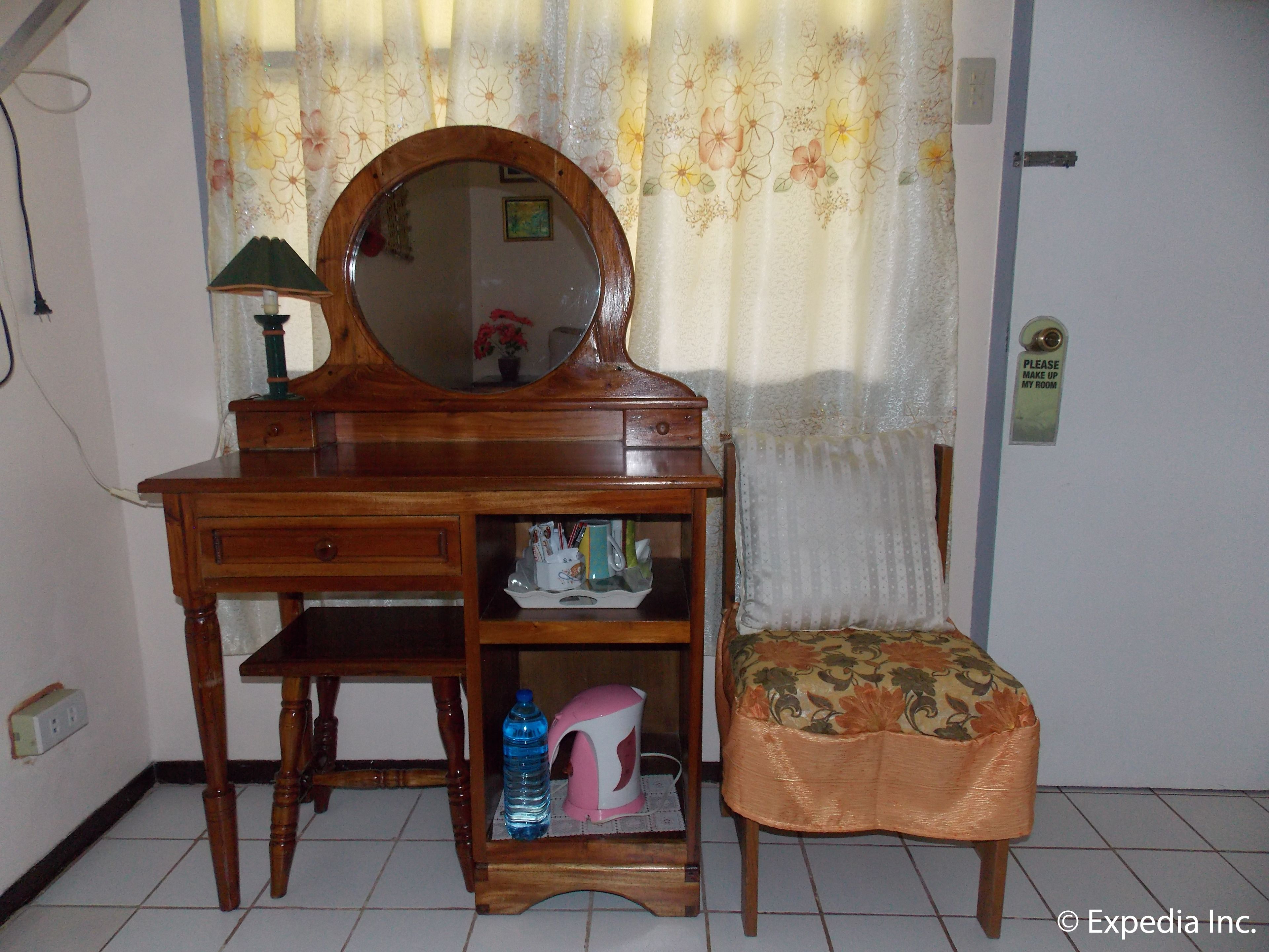 Un tocador de madera con espejo, una silla con cojín floral y un estante con artículos de aseo.