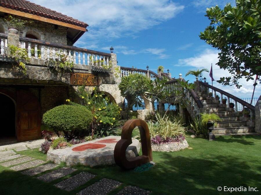 Un edificio histórico con fachada de piedra, un letrero que dice "Baluarte de Argao" y una escalera que conduce a un balcón.