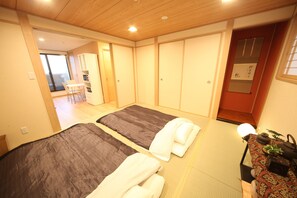 Ein Hotelzimmer mit zwei Betten, einem kleinen Tisch mit einer Pflanze und einer Schiebetür.