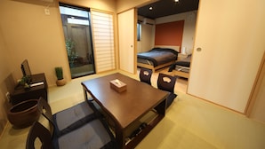 Une petite pièce avec une table en bois, un lit et une porte coulissante.
