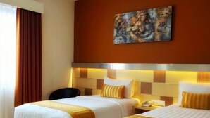 Ein Hotelzimmer mit zwei Betten, einem Bild an der Wand und einem Fenster mit Vorhängen.