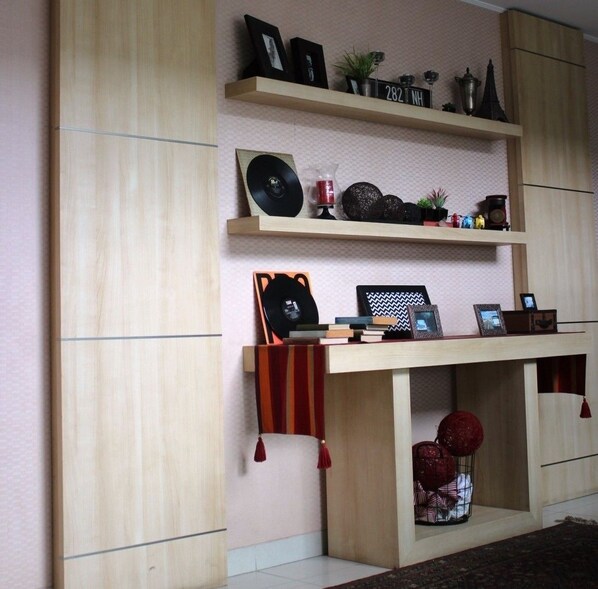 Una habitación con un mueble de madera que exhibe fotos enmarcadas, un disco de vinilo y objetos decorativos.
