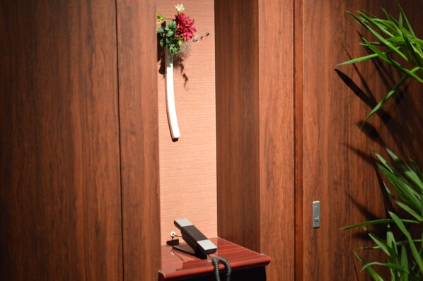 Une porte en bois, avec un téléphone et un arrangement floral posés sur une petite table.