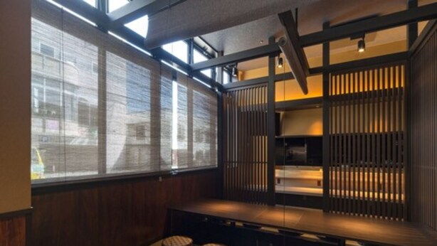 A traditional Japanese-style room with tatami flooring, low wooden tables, and a view of the city through large windows. - Queen's Hotel Chitose (Chitose)