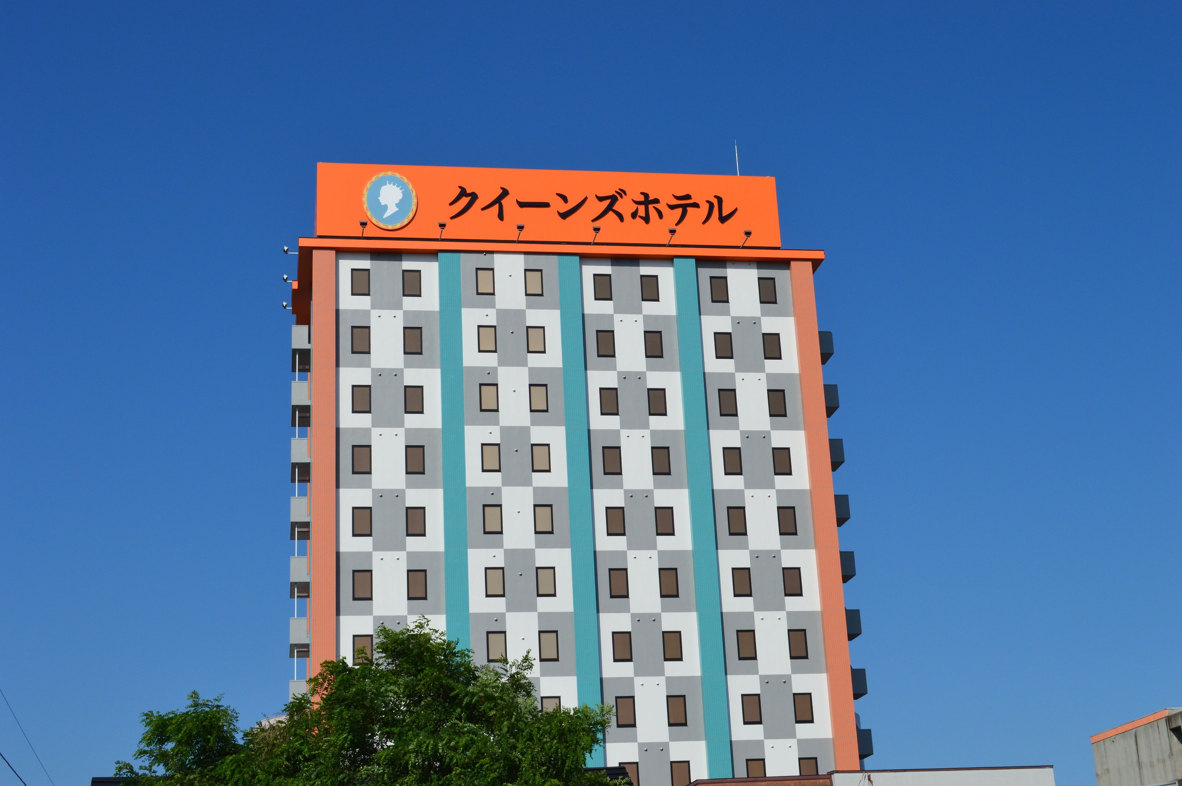 A hotel with a checkered facade and an orange sign with Japanese text.
