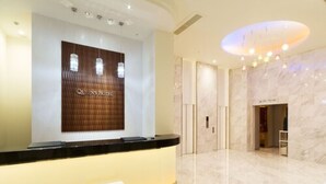 A hotel reception area with a marble floor, a reception desk, and a large sign above it. - Queen's Hotel Chitose (Chitose)