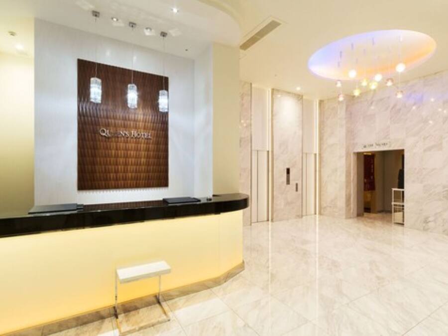 A hotel reception area with a marble floor, a reception desk, and a large sign above it.